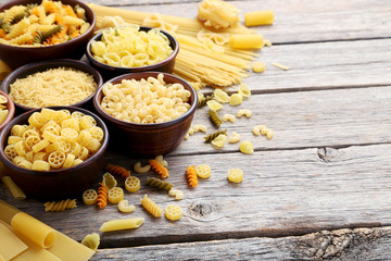 Different kinds of pasta in bowls on grey table