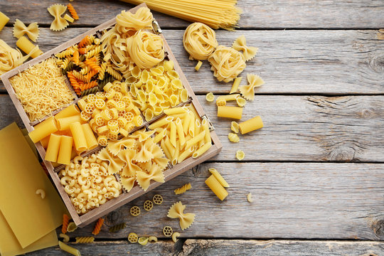 Different kinds of pasta on grey wooden table