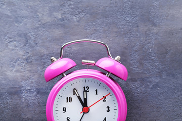 Pink alarm clock on grey wooden table