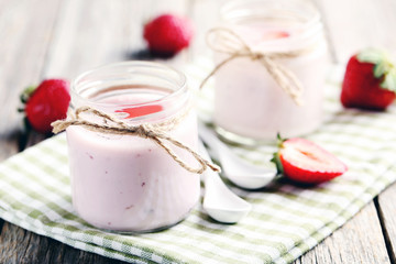 Strawberry yogurt in glass on a grey wooden table