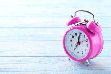 Pink alarm clock on blue wooden table