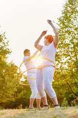 Two senior woman making fitness exercises with hoops