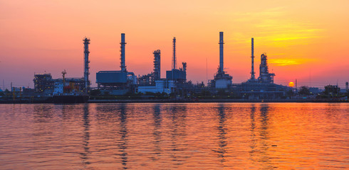Naklejka premium silhouette oil refinery industry at morning with golden sky.