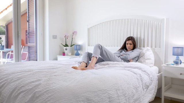 Woman in bed going under blanket feeling ill