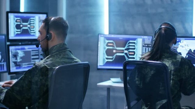 Female  and Male Military Technical Support Professional Giving Instructions into Headsets. They're in System Control Room with Many Working Screens. Shot on RED EPIC-W 8K Helium Cinema Camera.