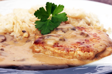 Delicious rice with chicken and vegetables on plate on wooden table