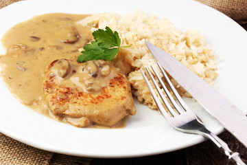 Delicious rice with chicken and vegetables on plate on wooden table