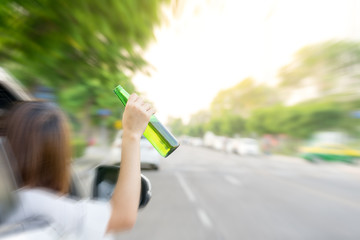 Drunk woman driving and holding beer bottle outside a car.