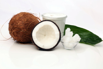 Coconut with leaves and coconut oil in jar on wooden background