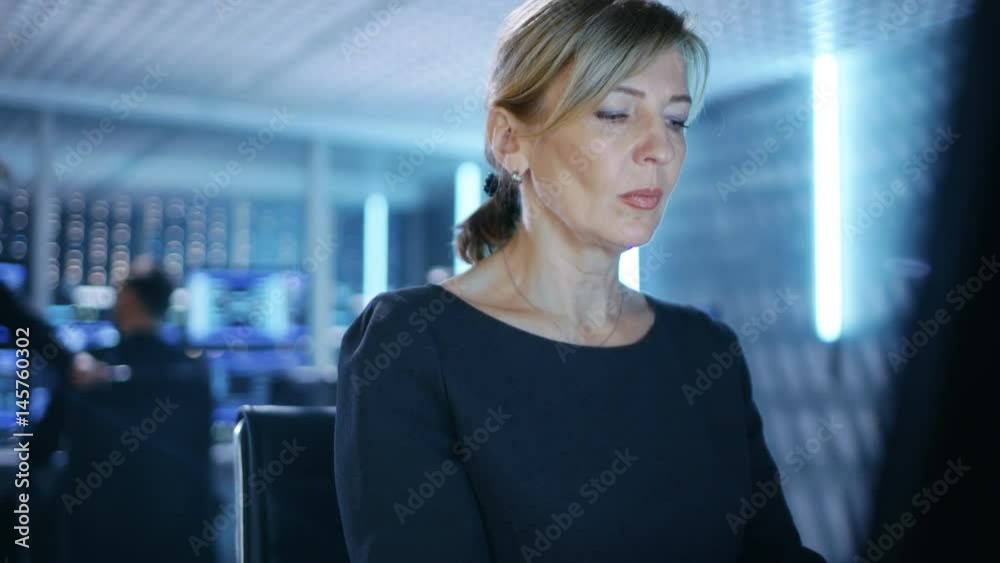 Poster Female IT Engineer Works on Her Desktop Computer in Government Surveillance Agency. In the Background People at Their Workstations with Multiple Screens Showing Graphics. Shot on RED EPIC-W 8K 