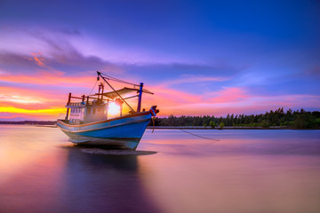 Fishing boat in tropical beach with beautiful sunset time.