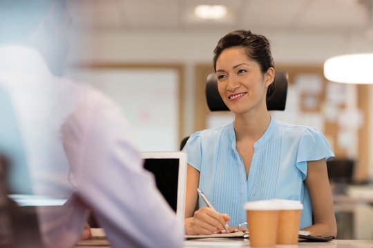 Smiling businesswoman discussing with male colleague in office
