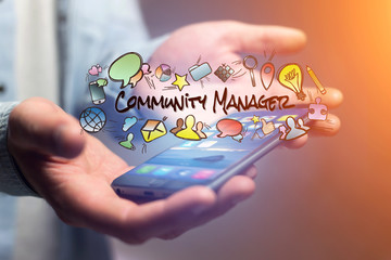Concept of man holding smartphone with community manager title and multimedia icons flying around