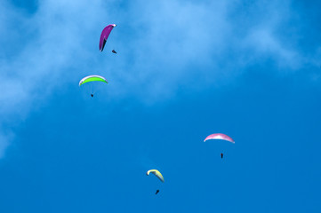 Paragliding in the blue sunny sky. One paraglider fly in summer sunny day in the clouds. Carpathians, Ukraine. Paragliding over the mountain valley.