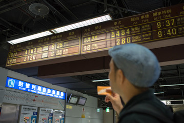 Man checking train timetable at Taipei Station in Taiwan　台北駅で時刻表を見る旅行者