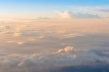 The colorful soft sky above the clouds and some mountains silhouettes below - airplane traveling in the summer