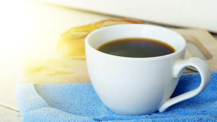 black coffee cup without sugar and fresh bread baked on white wood background