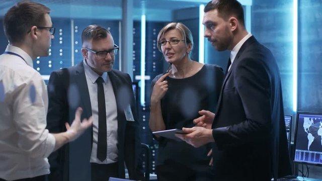 Team of Chief Engineers Have Emergency Meeting in System Controls Center. Man Holds Tablet. Computers in the Room Have Various Information on Their Screens. Shot on RED EPIC-W 8K Helium Cinema Camera.