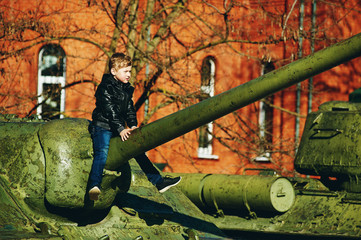 a boy plays on military equipment. Victory day