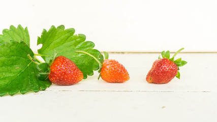 Fresh strawberries with leaf on old white wooden background