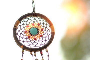 Obraz premium Dreamcatcher on the tree with green natural blurred bokeh background.