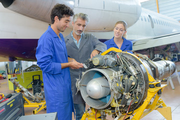 Students and teacher looking at aircraft turbine