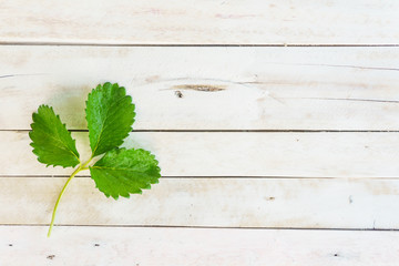 green leaf strawberries on white wooden background