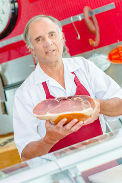 Butcher holding joint of cured ham