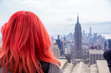 Fototapeta na wymiar New York - rothaarige Frau auf dem Dach des Top of the Rock schaut aufs Empire State Building
