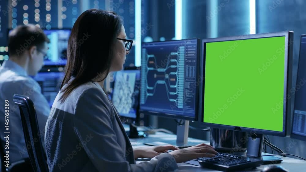 Poster Female Controller/ Operator Working at His Workstation with Multiple Displays (Green Screen Mock-up). Possible Power Plant/ Airport Dispatcher/ Dam Worker/ Government Surveillance/ Space Program. 