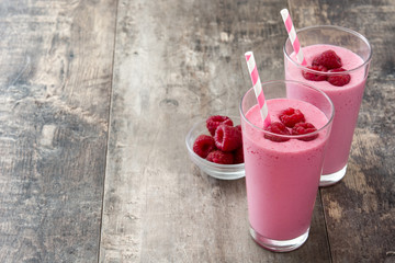 Raspberry smoothie in glass on wooden table
