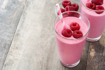Raspberry smoothie in glass on wooden table
