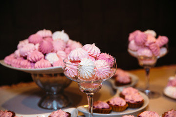 Sweet multilevel white wedding cake decorated with pink bottles of champagne. Candy bar