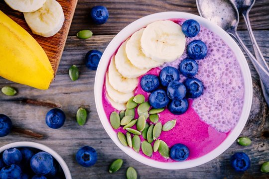 Healthy breakfast: purple smoothie bowl with chia pudding, banana, fresh blueberries and pumpkin seeds