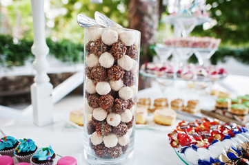 Table catering with different cakes and cupcakes at wedding reception.