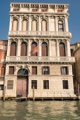 Fototapeta na wymiar Venetian palace with carved columns and arch windows on grand canal.