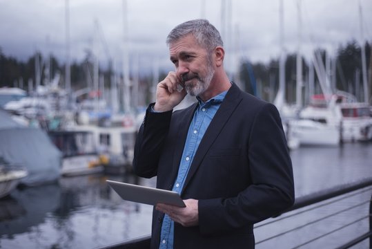 Businessman using smart phone by harbor