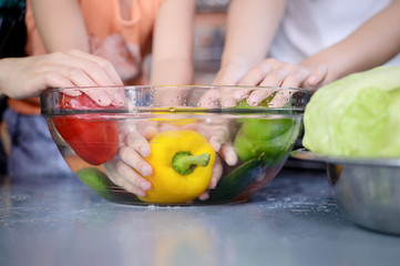 Hands washing fresh vegetables paprika red, green, yellow, in glass bowl