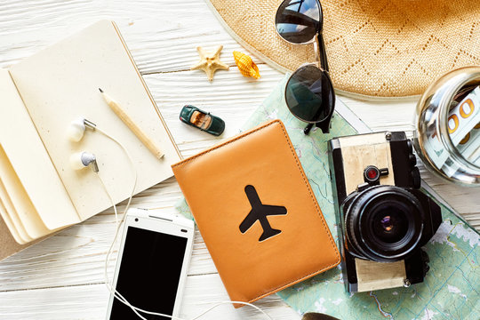 time to travel concept and wanderlust, space for text. map camera passport money phone with empty screen sunglasses hat shells car toy on white wooden background. hello holiday, planning vacation