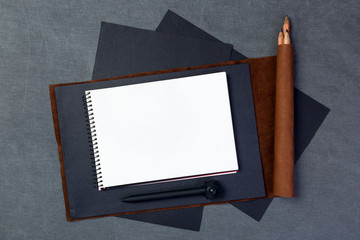 Open blank notepad with empty pages with a pen on gray and black texture