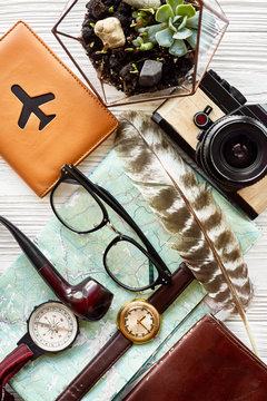time to travel concept, hipster flat lay. map passport money compass and glasses photo camera pipe on white wooden background top view. planning vacation. space for text, wanderlust and explore.