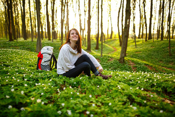 Young hiker woman with backpack on a forest trail. Smiling happy woman