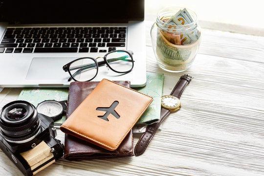 travel and wanderlust concept, planning summer vacation, space for text. jar with money map compass photo camera glasses wallet  watch laptop on white wooden background. time to travel