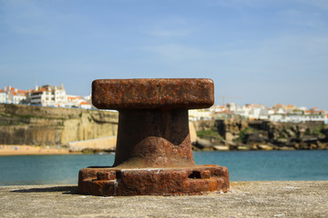 Old rusty steel mooring bollard pole on a pier