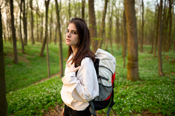 A young hiker resting with a backpack in a spring forest