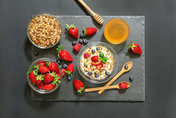 Breakfast of greek yogurt with berries, granola and honey.