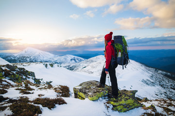 Woman with backpack trekking in mountains. Cold weather, snow on hills. Winter hiking. Recreation...