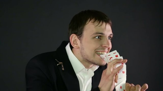 magician shows trick with card on black background.