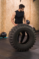 Sport Fitness Man Flipping Wheel Tire Crossfit Training, Young Healthy Guy Gym Interior