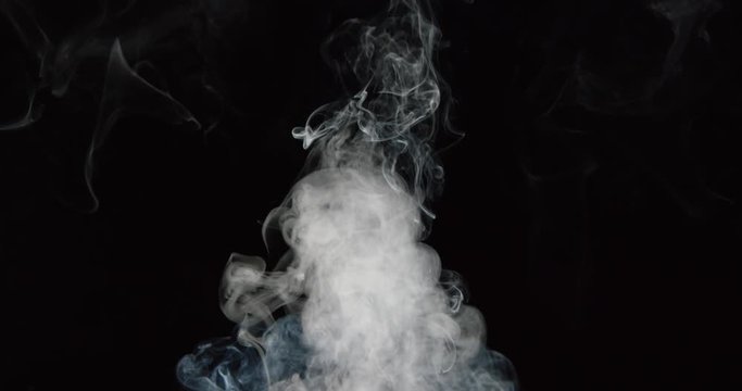 Smoke billows up into frame against black background, as if from fire